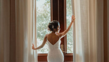 Bride looking out glass doors overlooking ceremony lawn Garey House